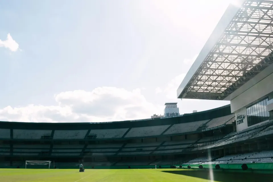 An empty football stadium with a green pitch
